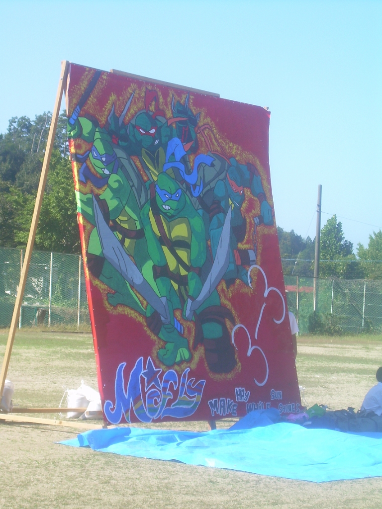 dscn0770.jpg - Another class's banner featured Ninja Turtles.  My next picture (not shown to protect student privacy) has a whole class sitting clustered together on the tarp in front of their banner, with all their shoes lined up neatly around the edge.